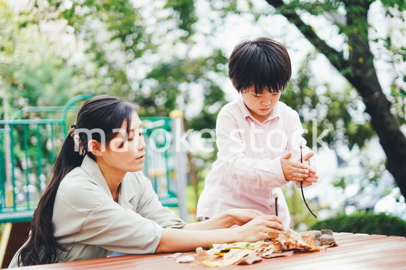 葉っぱで遊ぶお母さんと息子
