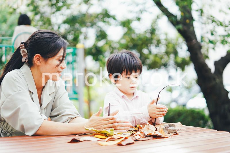 葉っぱで遊ぶお母さんと息子