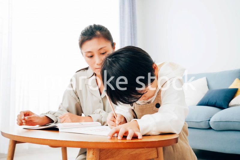 家でお母さんと一緒に勉強をする男の子