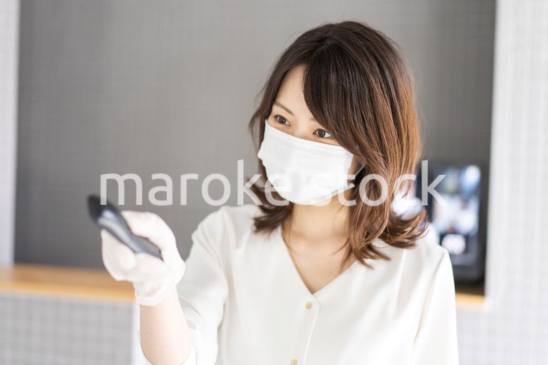 感染拡大防止のためにお客様の体温を計測するスタッフ