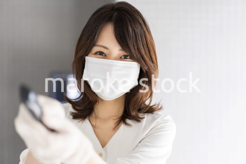 感染拡大防止のためにお客様の体温を計測するスタッフ