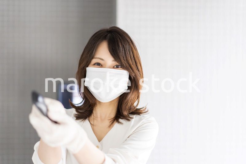 感染拡大防止のためにお客様の体温を計測するスタッフ