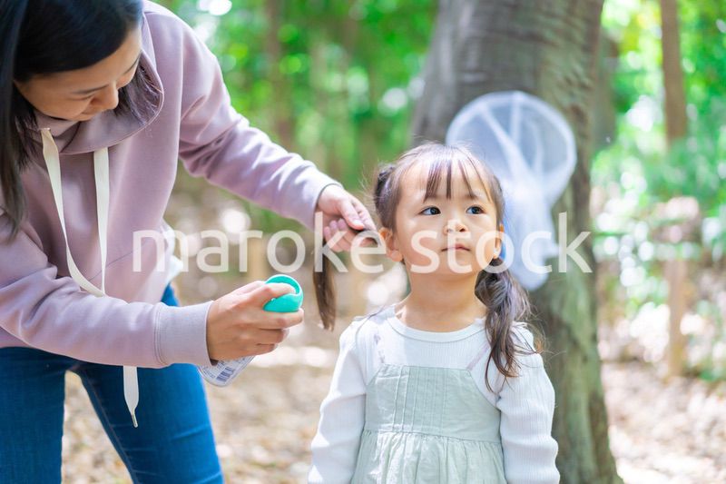 子供に虫除けスプレーをつけるお母さん