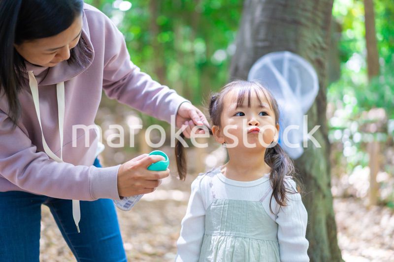 子供に虫除けスプレーをつけるお母さん
