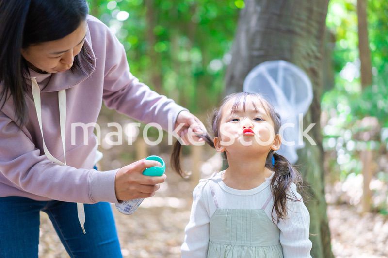 子供に虫除けスプレーをつけるお母さん