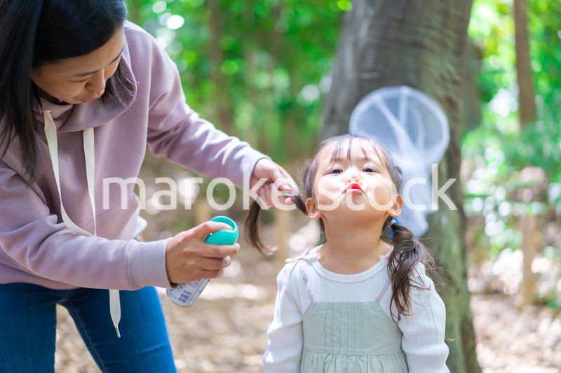 子供に虫除けスプレーをつけるお母さん