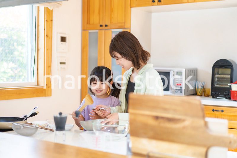 お母さんと一緒に料理をする小さな女の子
