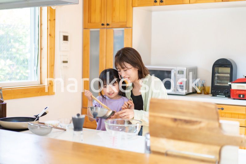 お母さんと一緒に料理をする小さな女の子