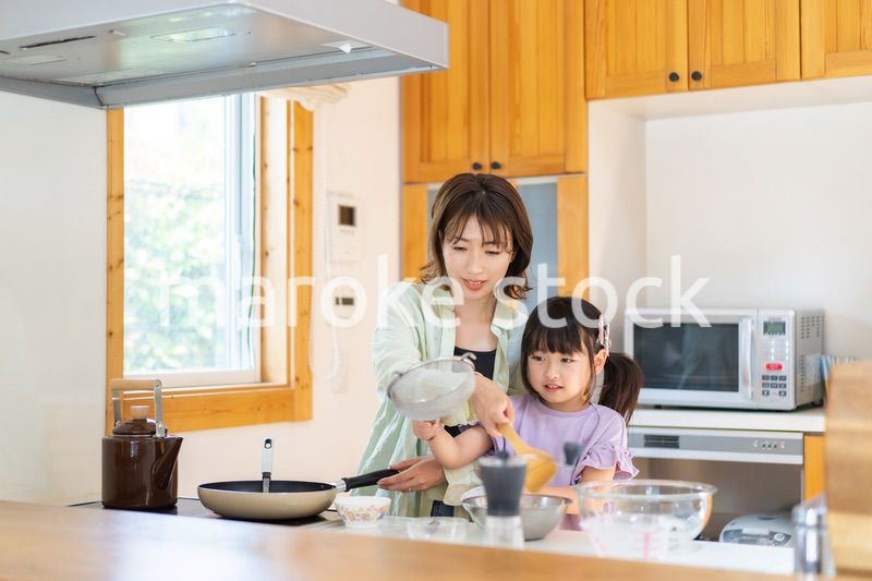 お母さんと一緒に料理をする小さな女の子