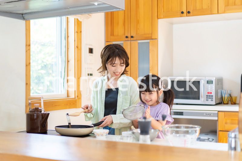 お母さんと一緒に料理をする小さな女の子