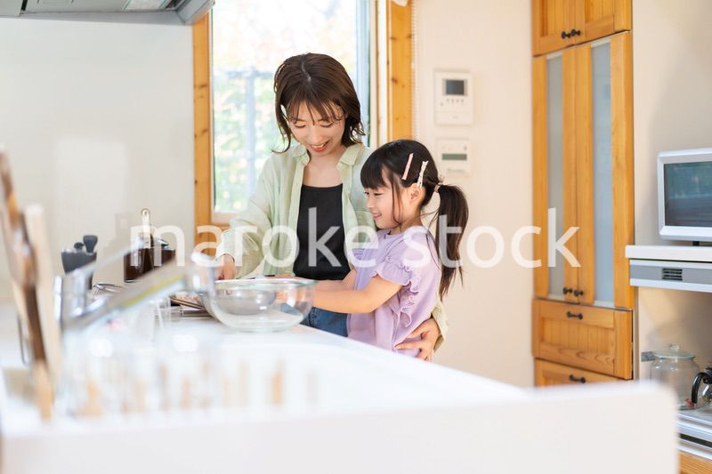 お母さんと一緒に料理をする小さな女の子