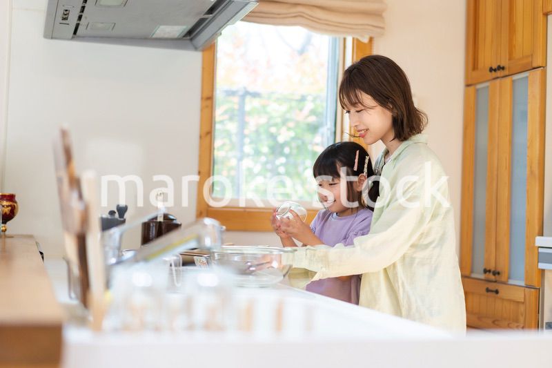 お母さんと一緒に料理をする小さな女の子