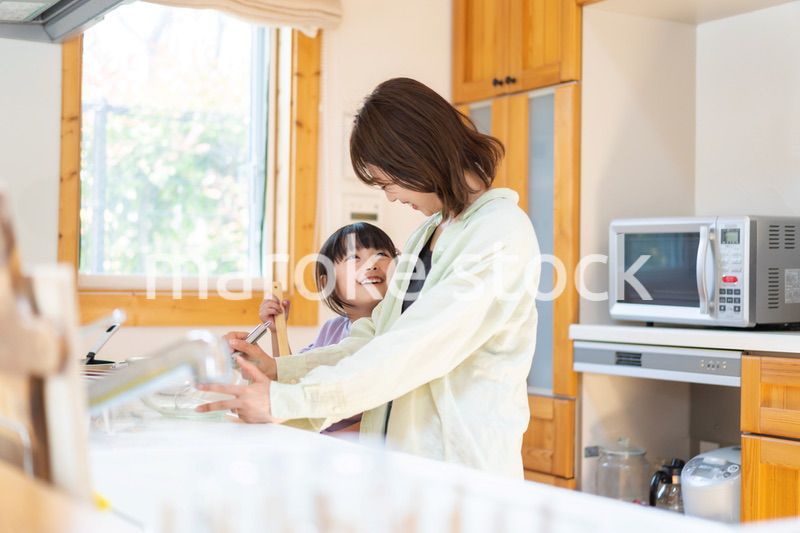 お母さんと一緒に料理をする小さな女の子