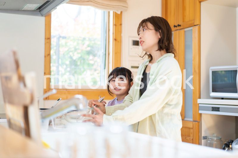 お母さんと一緒に料理をする小さな女の子