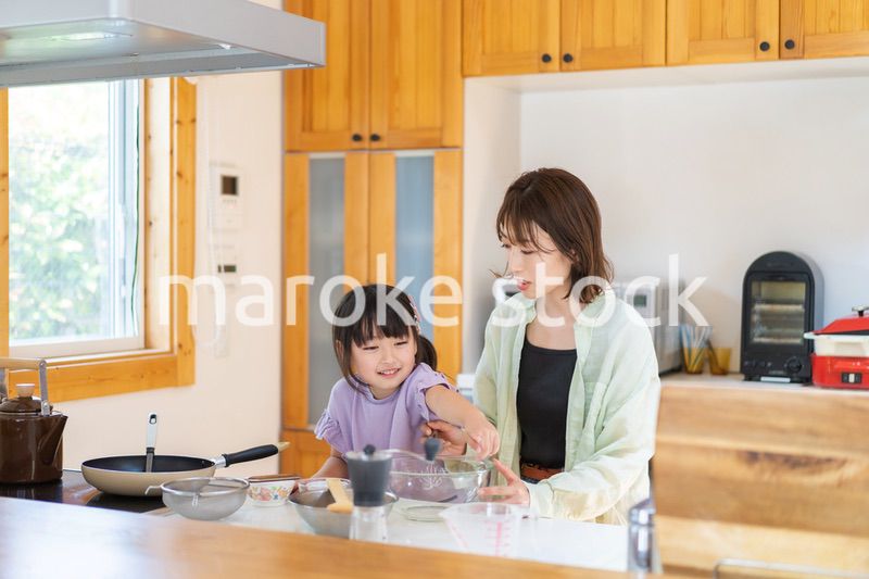 お母さんと一緒に料理をする小さな女の子
