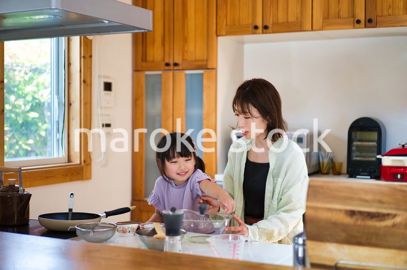 お母さんと一緒に料理をする女の子