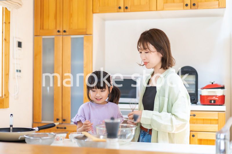 お母さんと一緒に料理をする小さな女の子