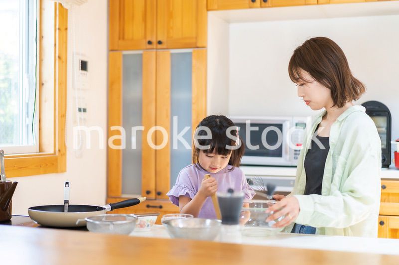 お母さんと一緒に料理をする小さな女の子