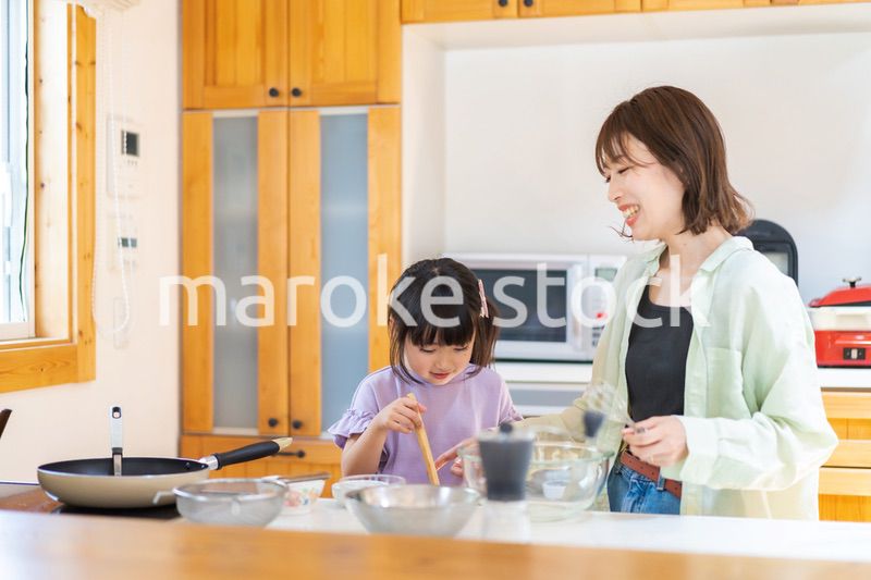 お母さんと一緒に料理をする小さな女の子