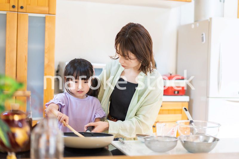 お母さんと一緒に料理をする小さな女の子