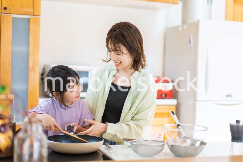 お母さんと一緒に料理をする小さな女の子