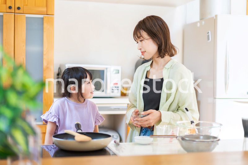 お母さんと一緒に料理をする小さな女の子