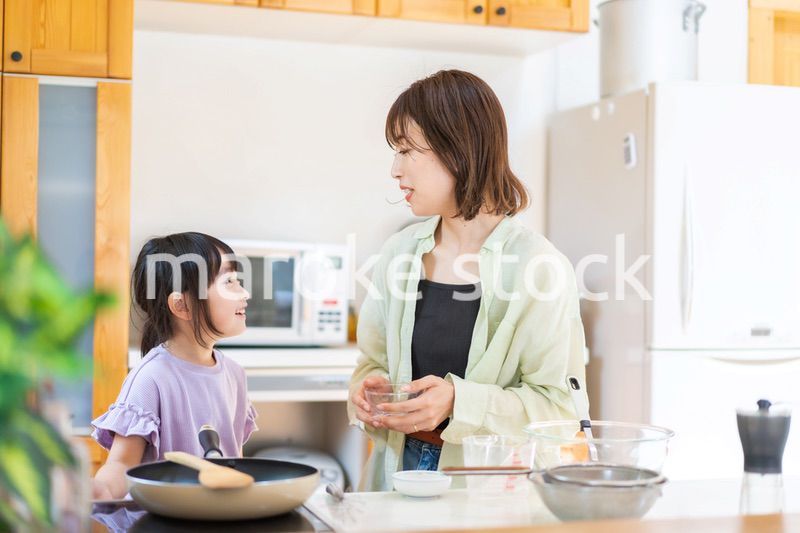 お母さんと一緒に料理をする小さな女の子