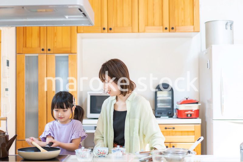 お母さんと一緒に料理をする小さな女の子