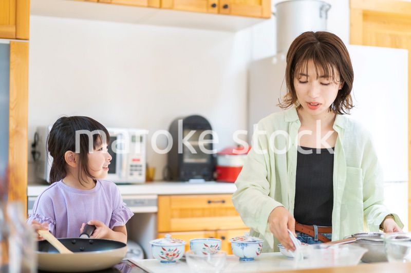 お母さんと一緒に料理をする小さな女の子