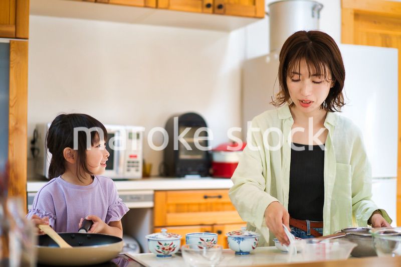 お母さんと一緒に料理をする女の子
