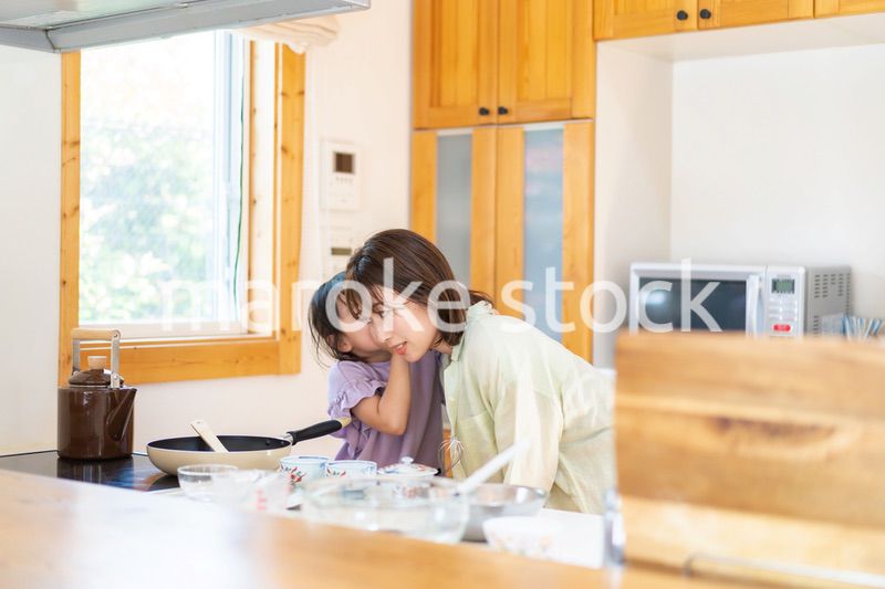 お母さんと一緒に料理をする小さな女の子