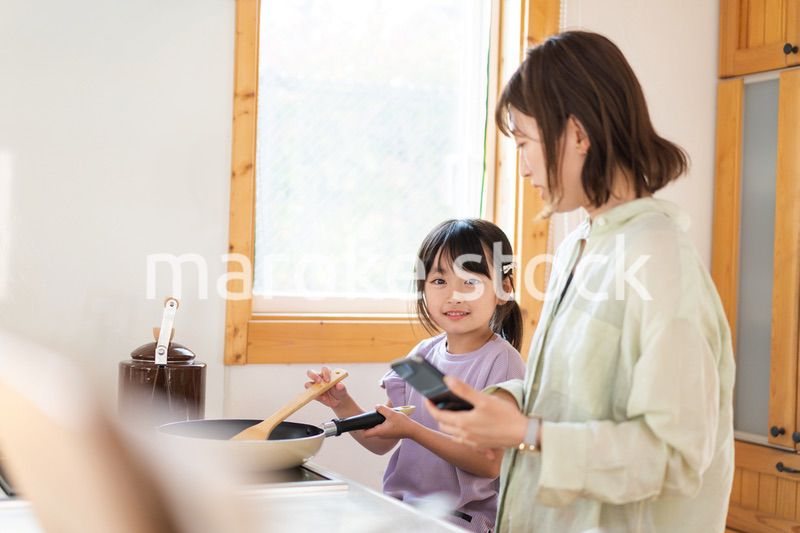 お母さんと一緒に料理をする小さな女の子