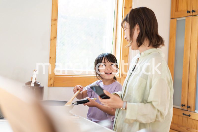 お母さんと一緒に料理をする小さな女の子