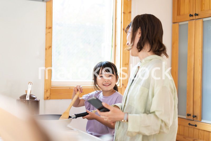 お母さんと一緒に料理をする小さな女の子