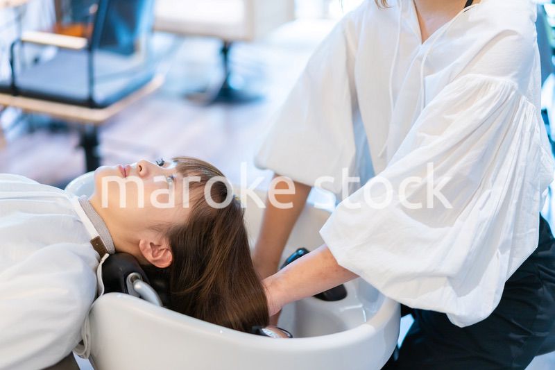 シャンプー台でシャンプーをする美容師