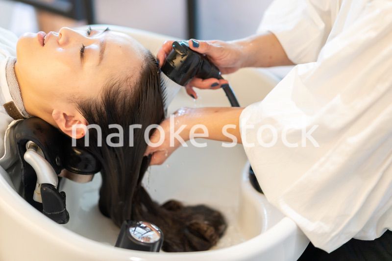 シャンプー台でシャンプーをする美容師