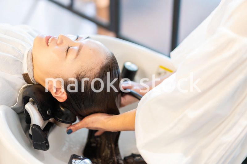 シャンプー台でシャンプーをする美容師