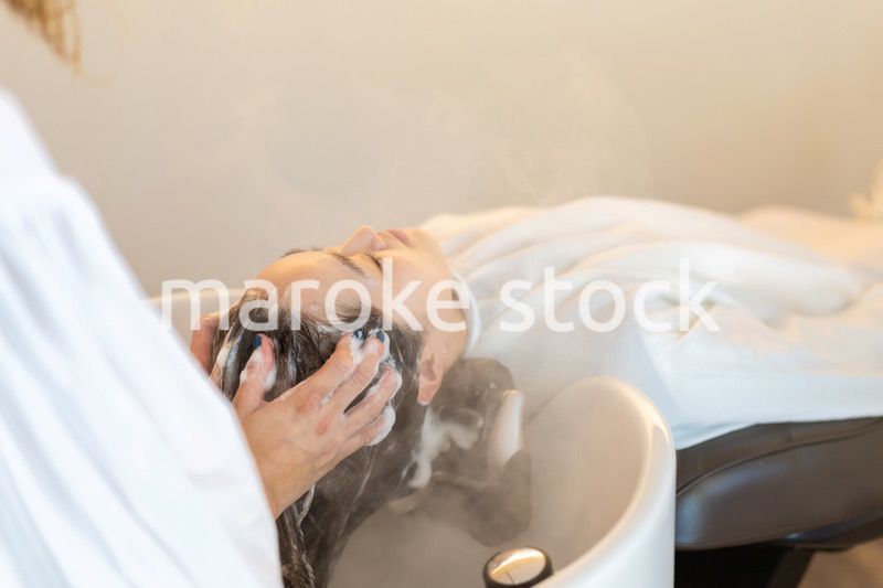 シャンプー台でシャンプーをする美容師