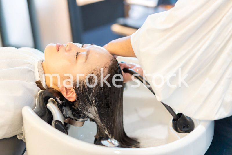 シャンプー台でシャンプーをする美容師