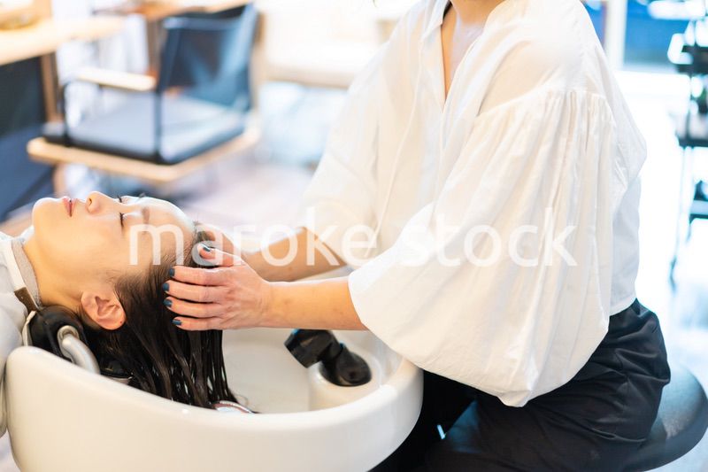 シャンプー台でシャンプーをする美容師