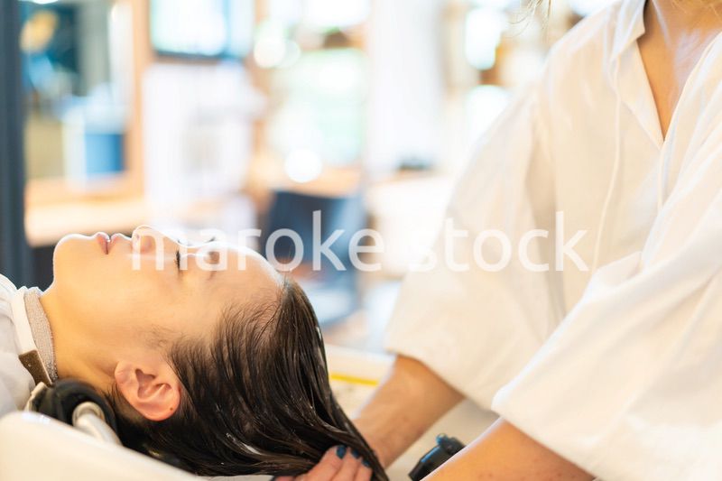 シャンプー台でシャンプーをする美容師
