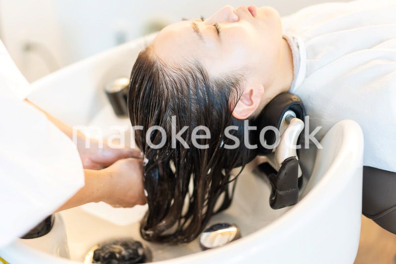 シャンプー台でシャンプーをする美容師