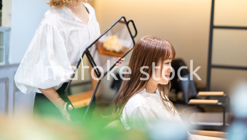 ミラーでヘアスタイルの確認をする美容師