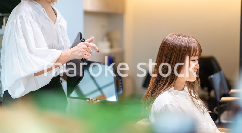 ミラーでヘアスタイルの確認をする美容師